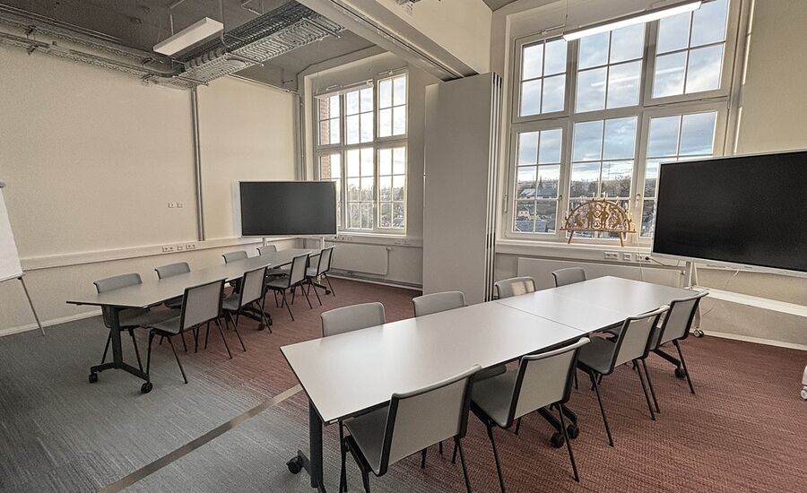 Verbundene Meetingräume mit 2 Tischen, Stühlen und digitalen Whiteboards