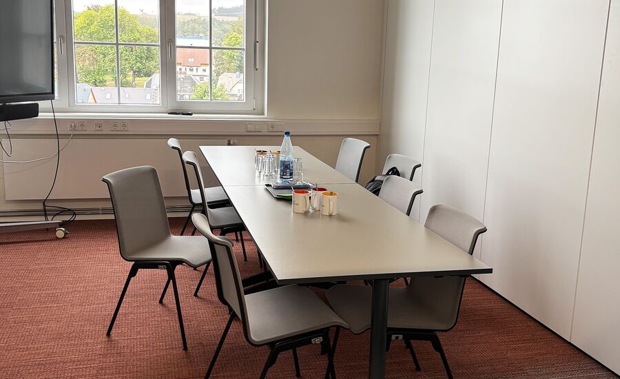 Meetingraum mit Tisch, Stühlen und Getränken