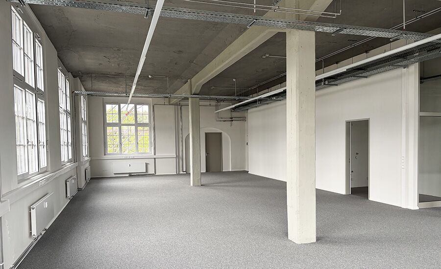 Ein modernes, helles Büro mit minimalistischer Gestaltung, in dem zwei Säulen im Zentrum des Raumes stehen